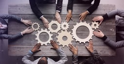 A group of people sitting at a table, aligning gears