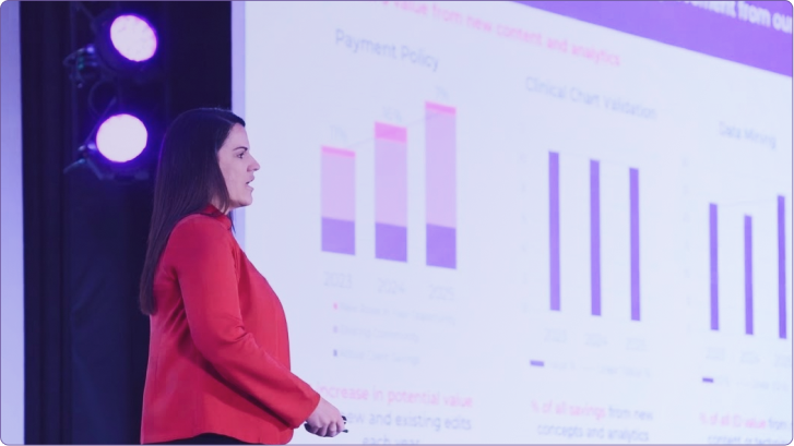 A speaker holding a microphone on stage in front of a crowd at a Cotiviti Client Conference