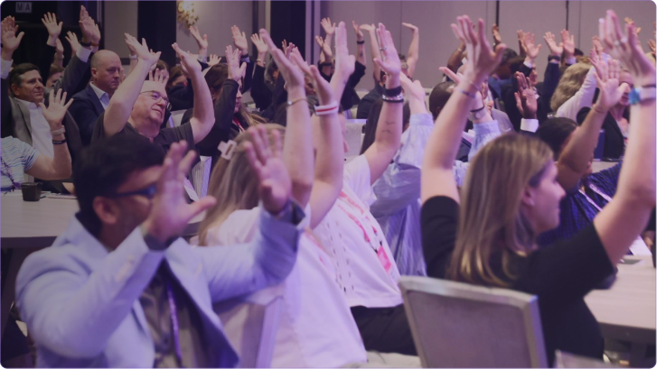 A speaker holding a microphone on stage in front of a crowd at a Cotiviti Client Conference