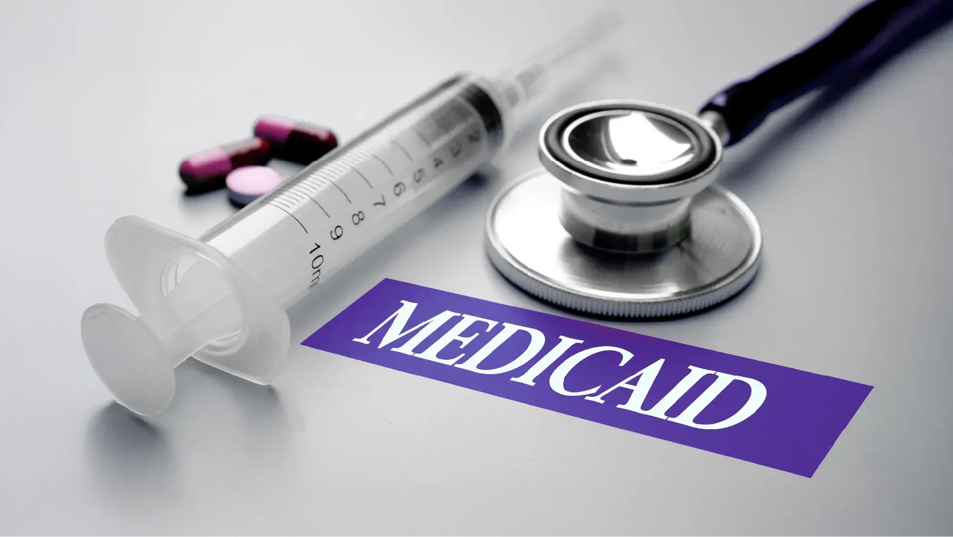 A syringe, stethoscope, and pills on a table